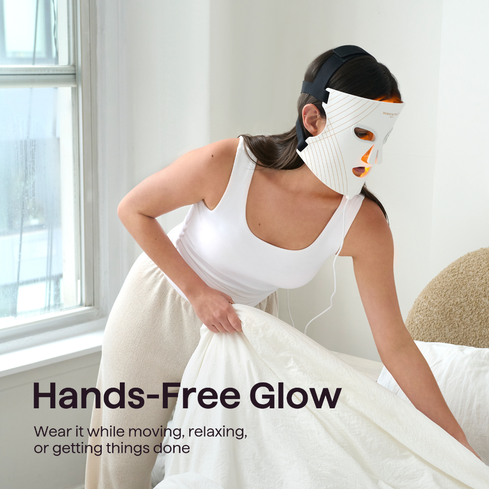 A woman wearing a white hands-free LED facial mask while pulling a white sheet, with the text 'Hands-Free Glow' in the lower left corner.
