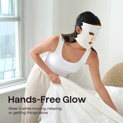 A woman wearing a white hands-free LED facial mask while pulling a white sheet, with the text 'Hands-Free Glow' in the lower left corner.