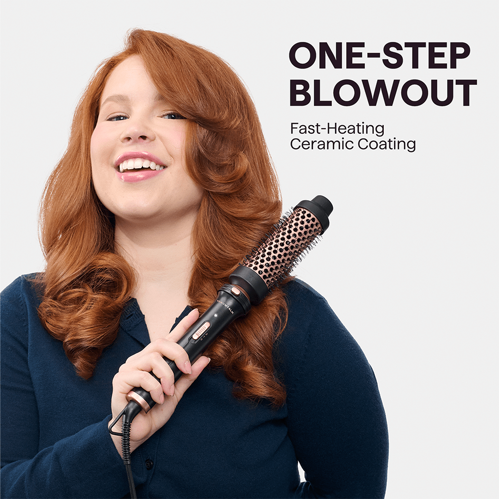 Woman with styled red hair using Pink Multi Curl 5-in-1 curling tool with 'One-Step Blowout' text on a light gray background.