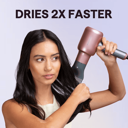 Rose Gold Blown Away hair dryer used by a woman to dry hair, featuring the text "Dries 2x Faster" on a light purple background.